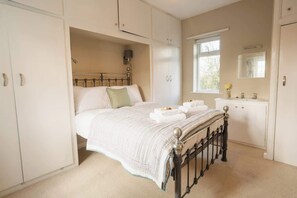 A bedroom with a bed, wardrobe, and a window.