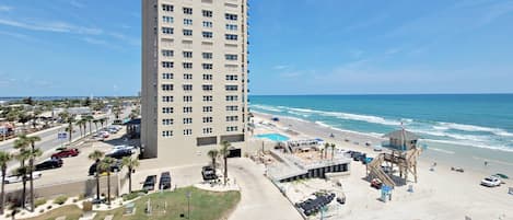 Un hotel de gran altura con vista a la playa, un estacionamiento y una torre de salvavidas.