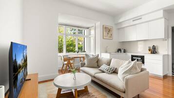 A modern living room with a sofa, coffee table, and a painting on the wall.