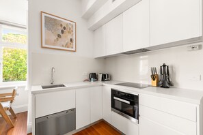 A modern kitchen with white cabinetry, a dishwasher, an oven, and a toaster.