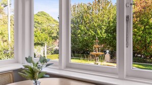 A room with a large window overlooking a garden with a fountain and trees. - Inner-West Studio in a Perfect Location (Lewisham)
