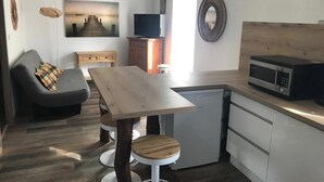 Une cuisine compacte avec une table en bois, un four à micro-ondes et un petit réfrigérateur.