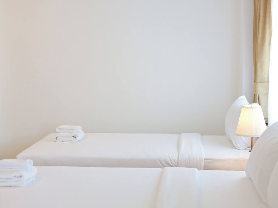 Habitación de hotel con dos camas, una lámpara y un ventanal con cortinas.