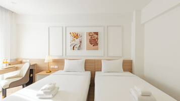 Une chambre d’hôtel avec deux lits, un bureau, une chaise et deux œuvres d’art accrochées au mur.