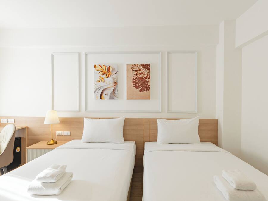 Habitación de hotel con dos camas, un escritorio, una silla y dos obras de arte colgadas en la pared.