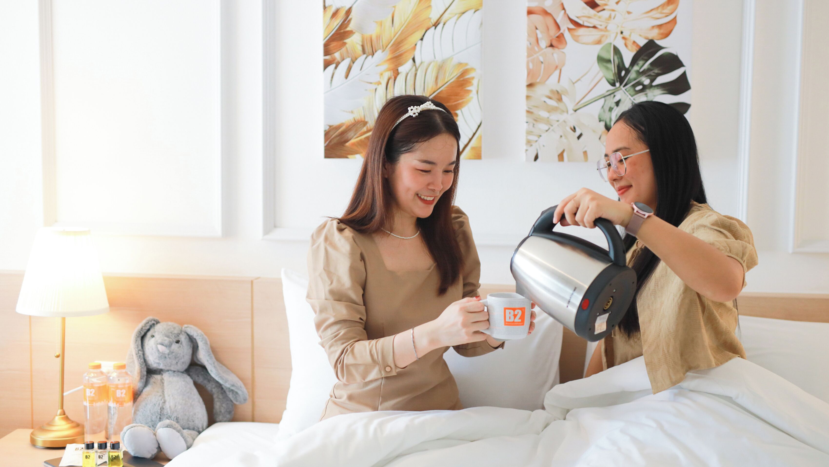 Two people in a bedroom, one pouring coffee into a mug.