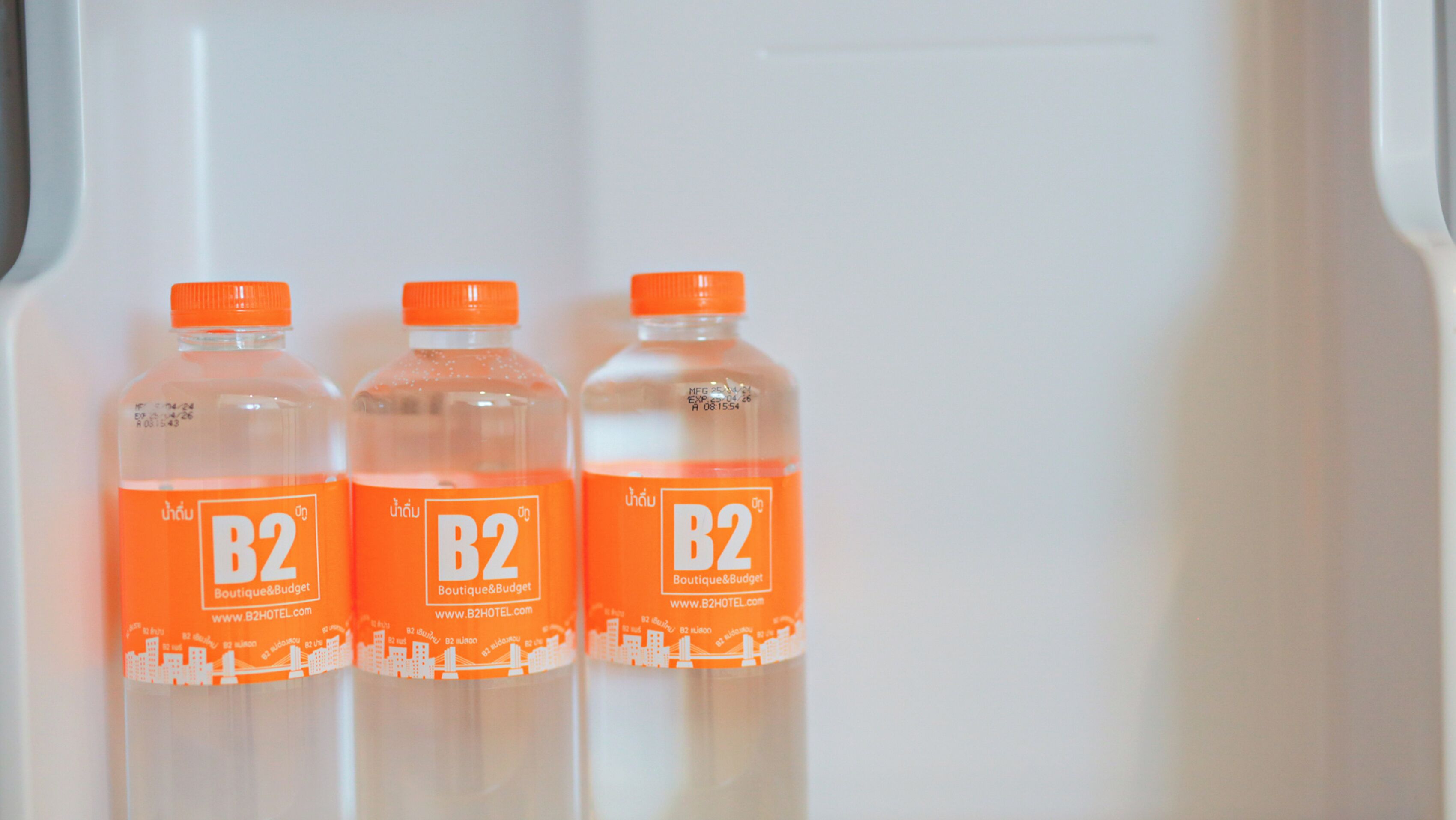 Three bottles of B2 orange liquid in a refrigerator.
