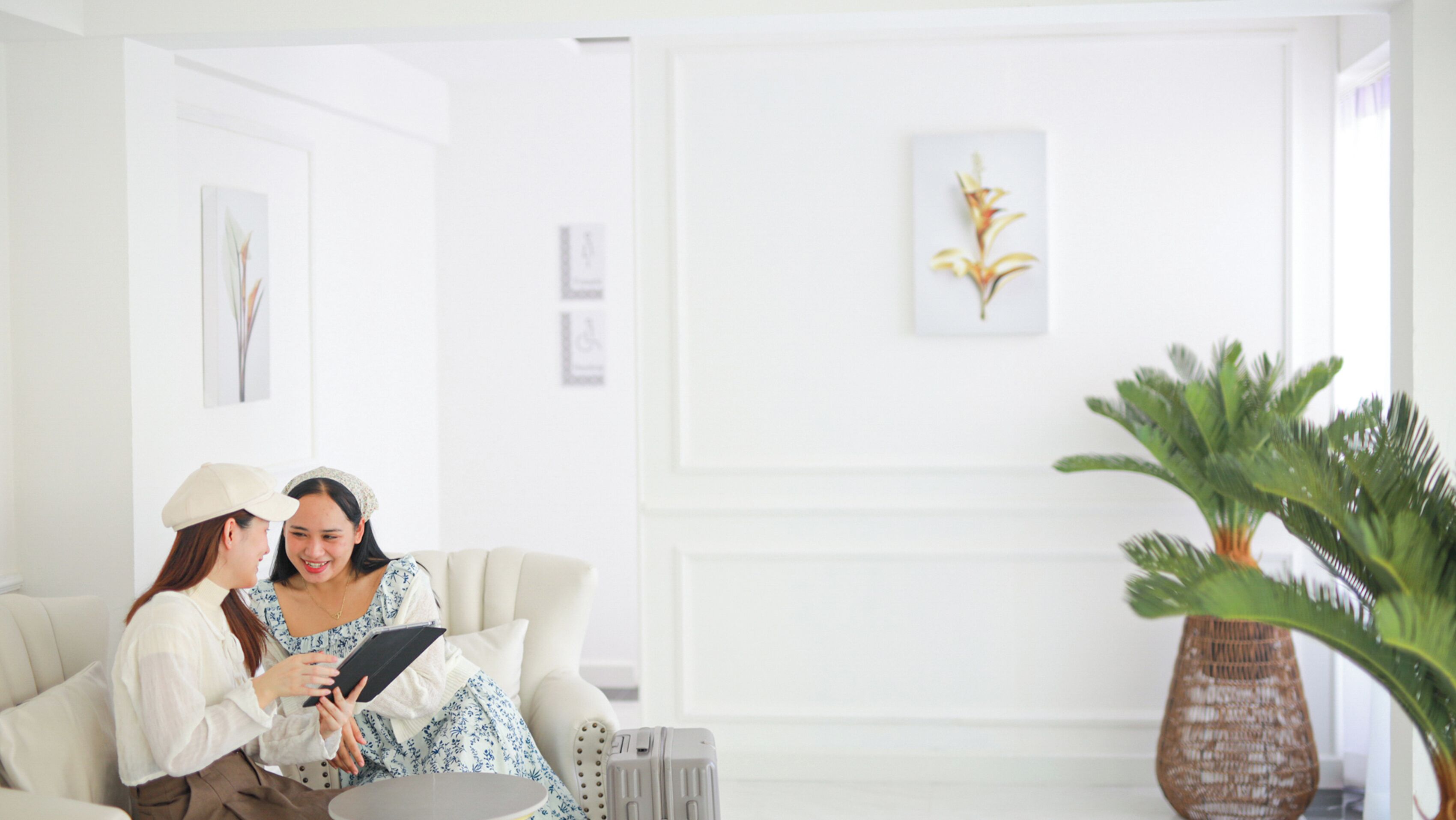 A modern living room with a white sofa, a small round table, and a potted plant.