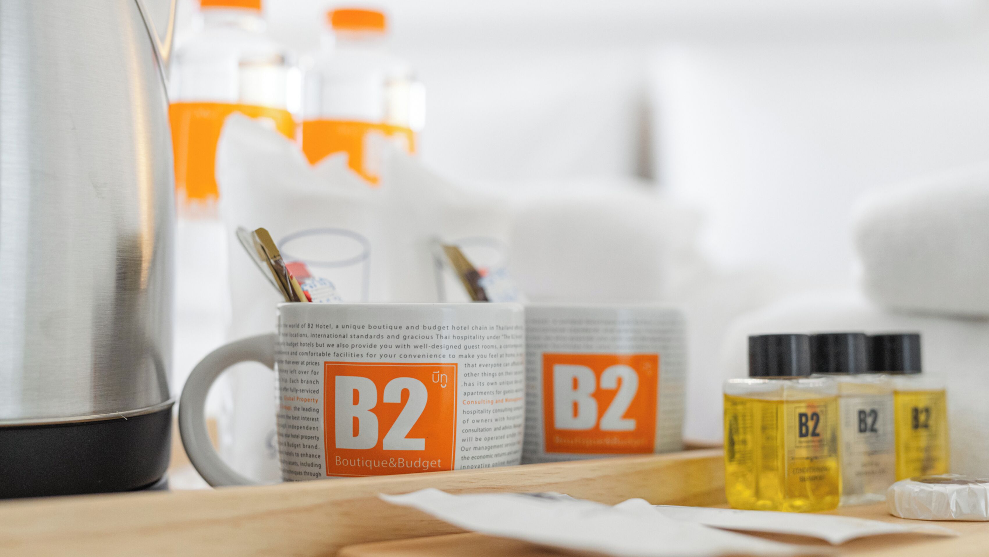 A table with B2 branded items, including a mug, bottles, and a kettle.
