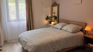 A bedroom with a bed, a bedside lamp, a nightstand with a mirror, and a window with curtains. - Secluded Périgourdine, nestled in the vineyards with a spa and a view (Pomport)