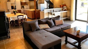 A modern kitchen with a central island, a dining area with a table and chairs, and a cozy living space with a sofa and a coffee table. - Secluded Périgourdine, nestled in the vineyards with a spa and a view (Pomport)