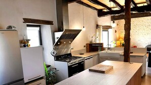 A modern kitchen with a central island, built-in appliances, and a rustic ceiling. - Secluded Périgourdine, nestled in the vineyards with a spa and a view (Pomport)