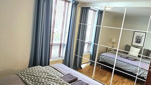 Ein Schlafzimmer mit einem großen Bett, einem Spiegel und Blick auf einen anderen Raum.