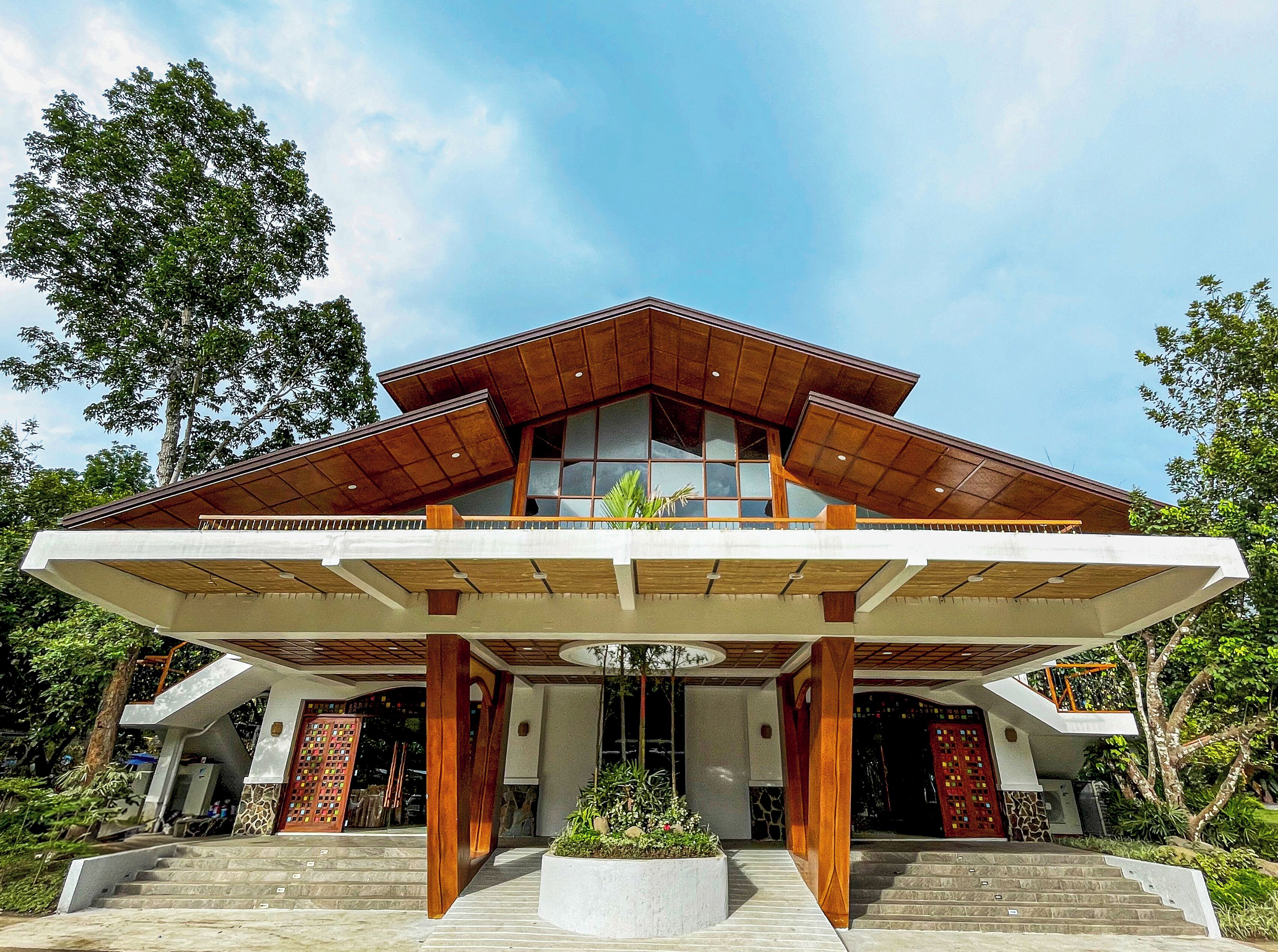 A modern building with a sloped roof, large windows, and a covered entrance area.