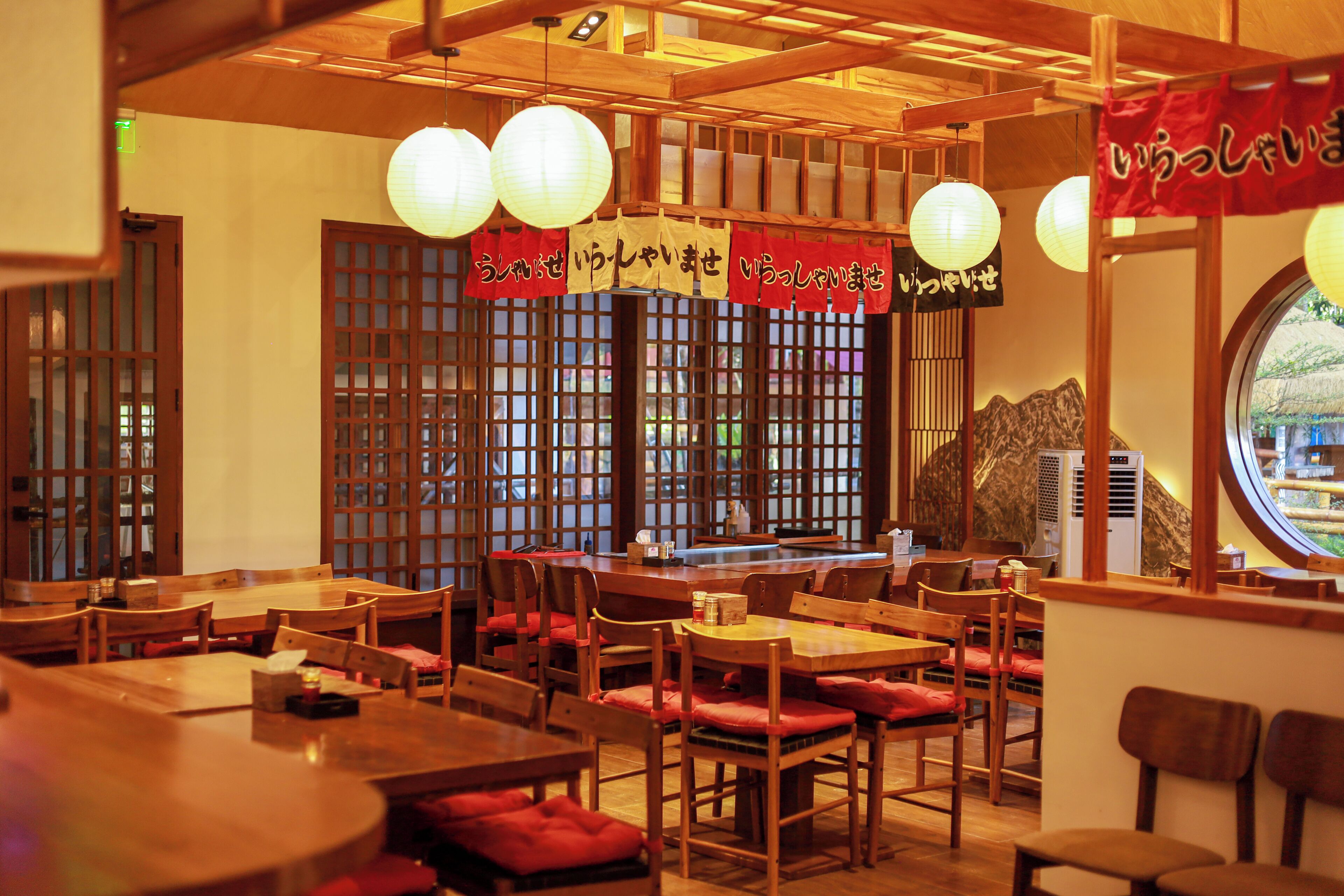 A traditional Japanese restaurant interior with wooden furniture, tatami mats, and paper lanterns.