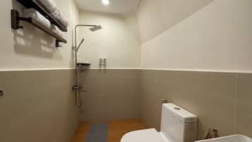 Een kleine, moderne badkamer met douche, toilet en wastafel.