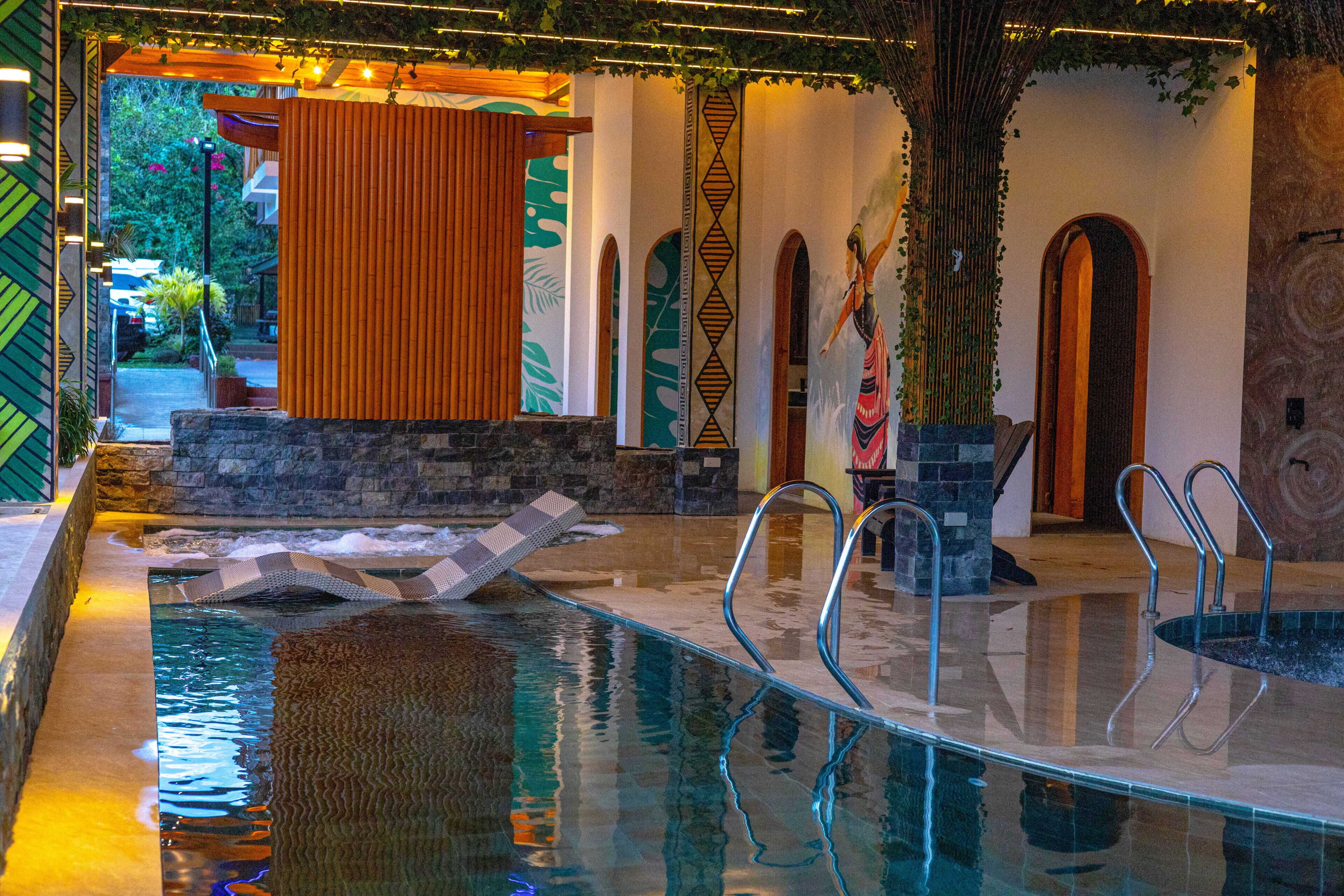 Ein Hallenbad mit klarem Wasser, Metallleiter und einer Steinwand.