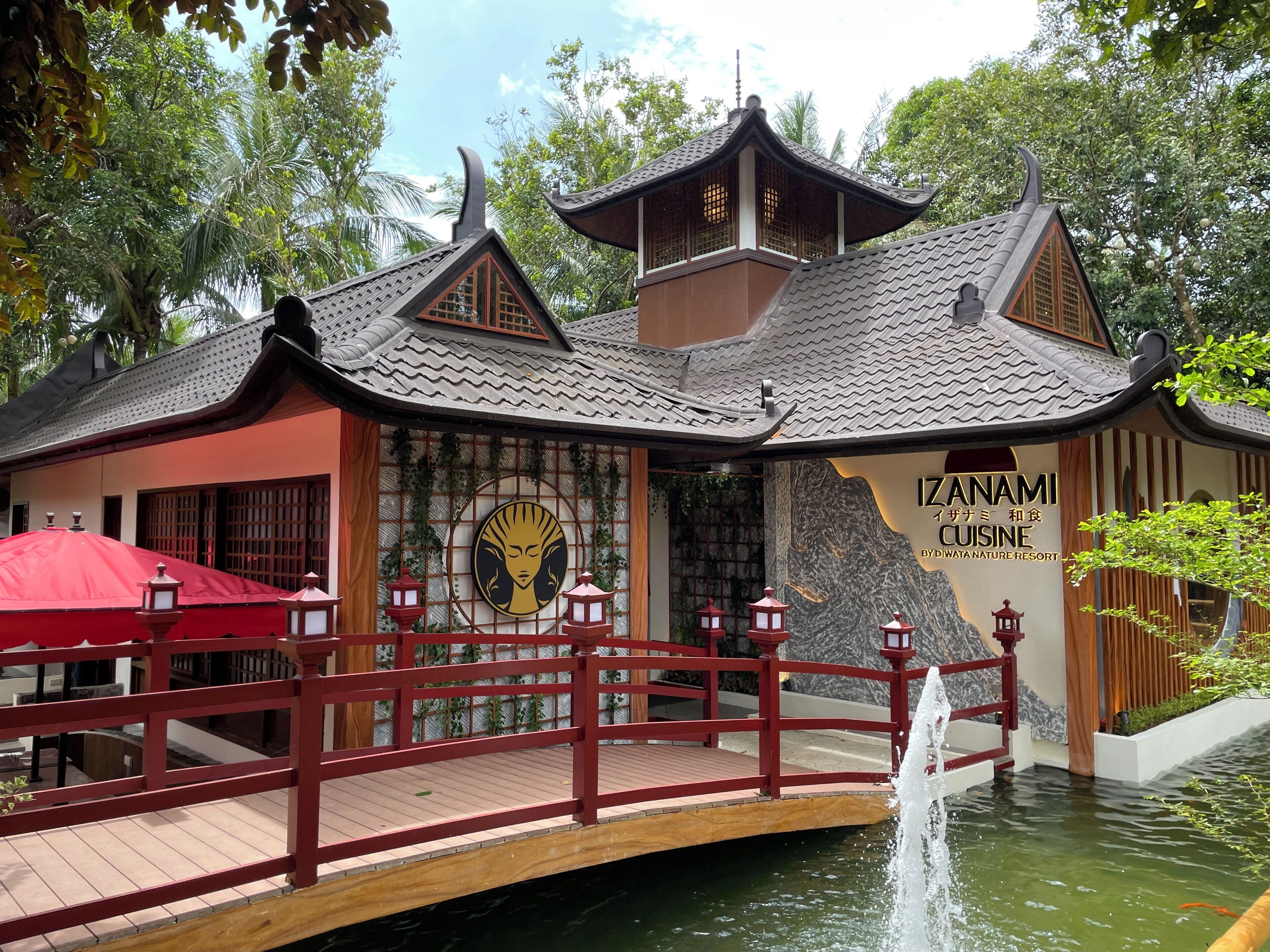 Ein traditionelles japanisches Gebäude mit einer roten Brücke und einem Brunnen.