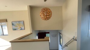 A modern interior with a wooden staircase, a hanging light fixture, and a framed artwork on the wall. - Sunny, family-friendly house with harbour views (Wellington)
