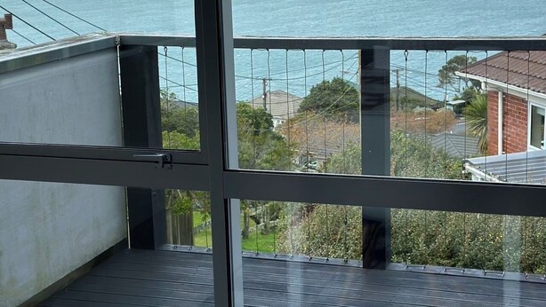A balcony with a view of the sea and houses in the distance. - Sunny, family-friendly house with harbour views (Wellington)