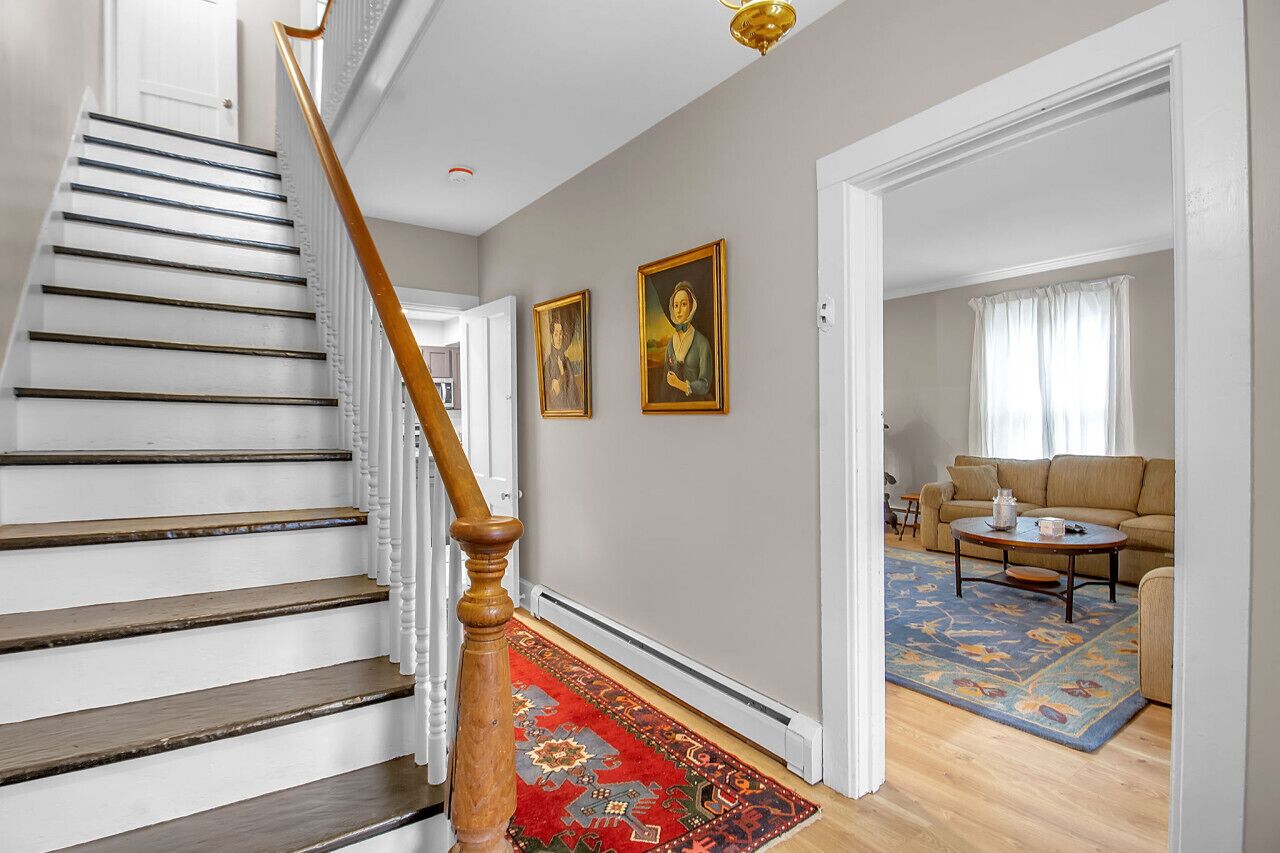 Un escalier avec des marches en bois et une rampe en bois, menant à un salon doté d’un canapé beige et d’une table basse.