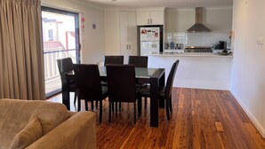 Un appartement moderne comprenant un coin repas, une cuisine et un balcon agrémenté de rideaux.