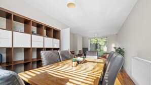Un coin repas comprenant une table en bois, des chaises et un meuble de rangement intégré avec des tiroirs.