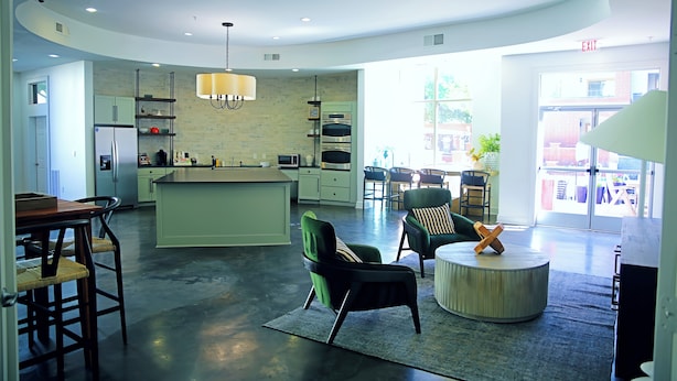 A modern kitchen with a central island, seating area with chairs, and a dining table.