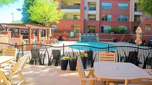 A rooftop pool area with outdoor seating and a brick building in the background.