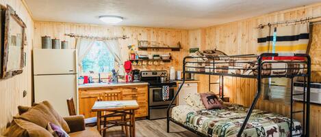A compact room with bunk beds, a kitchenette, a dining area, and a sofa.