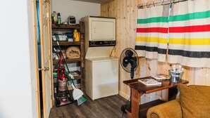 Una habitación pequeña con lavadora, ventilador y escoba.