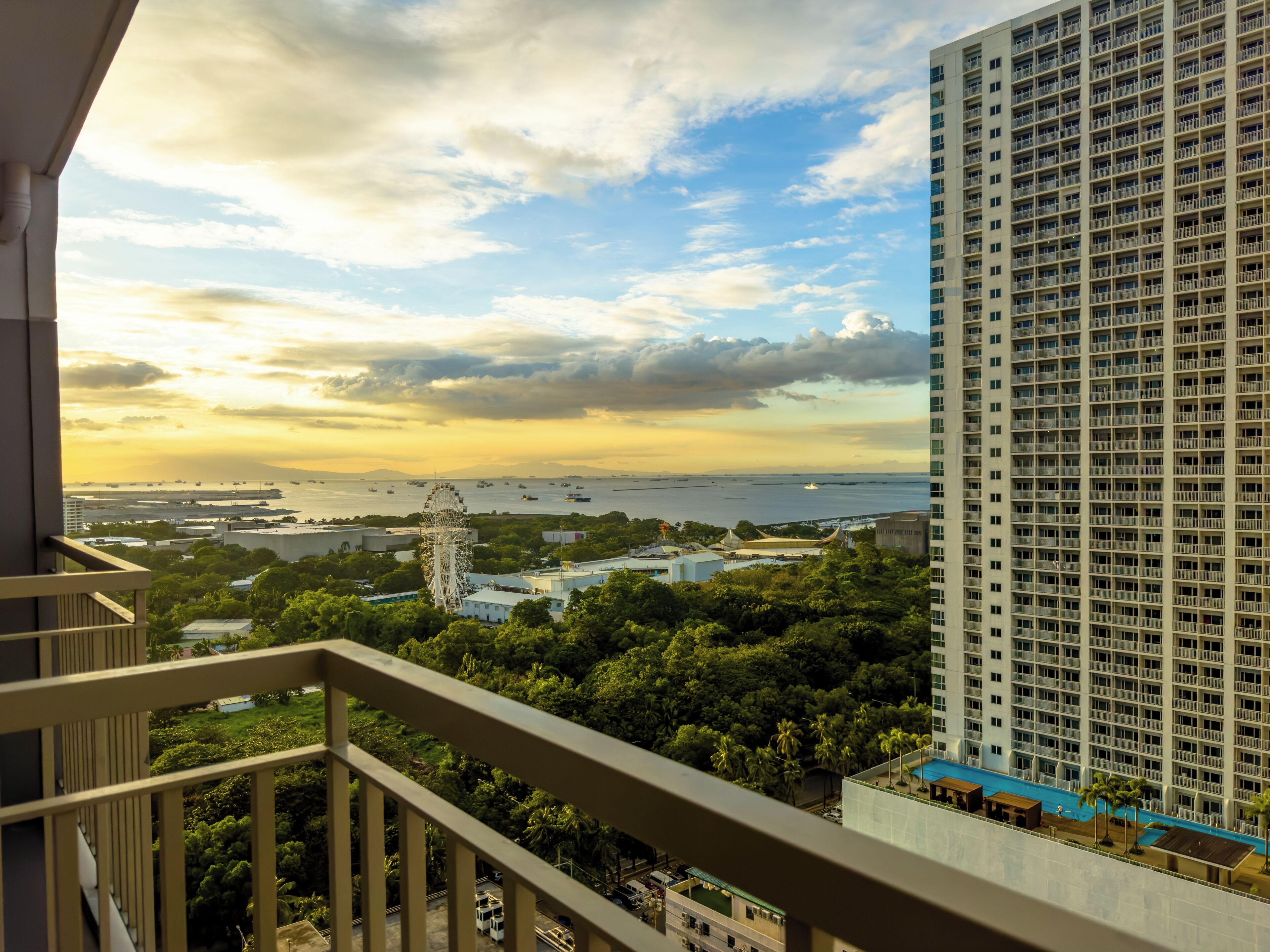 A high-rise building with a view of a waterfront and a Ferris wheel in the distance.