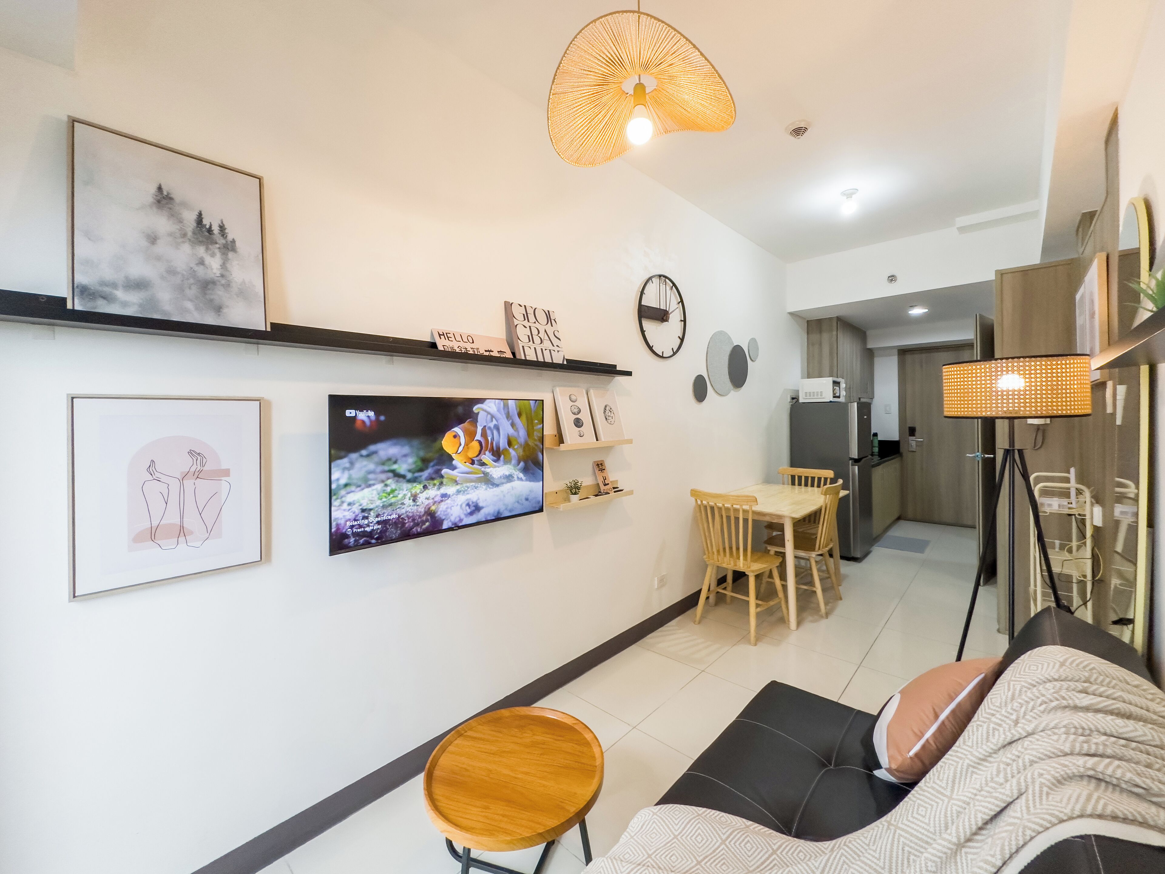 Una sala de estar moderna con un televisor de pantalla plana, una mesa de comedor de madera y un sofá.