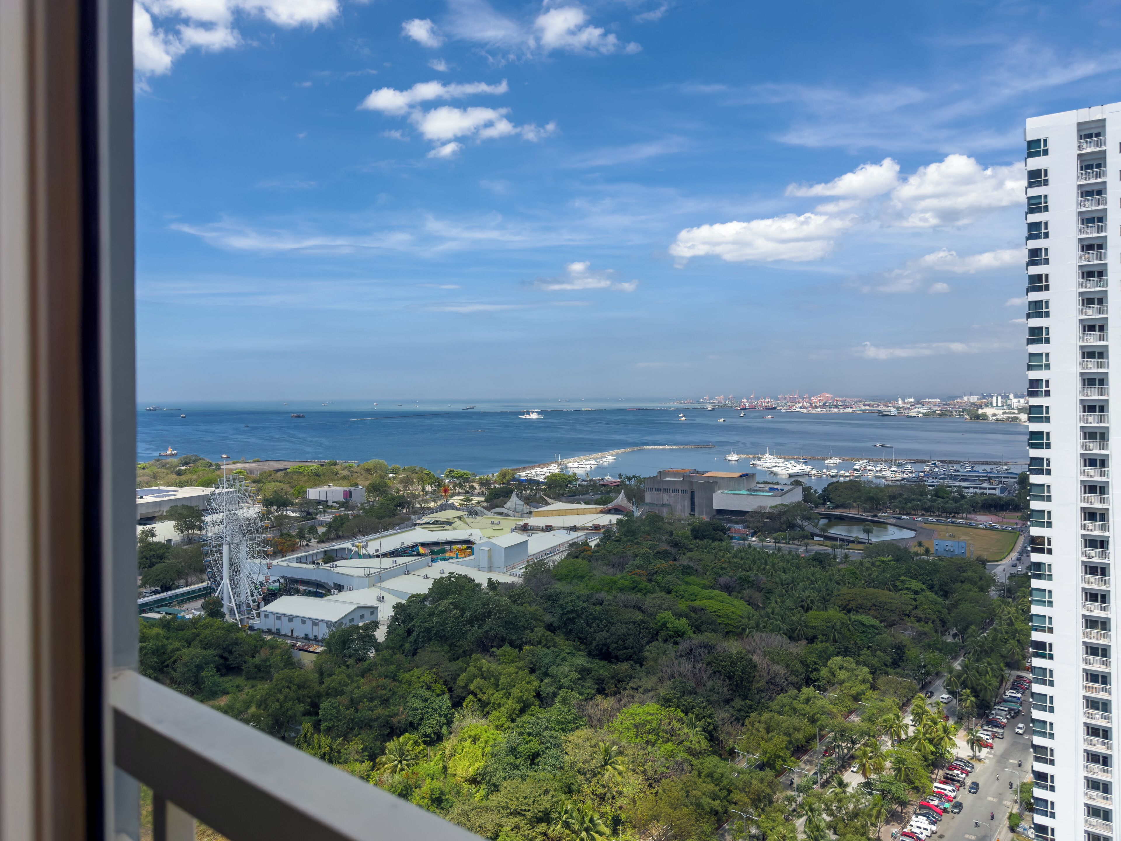 Un paisaje urbano costero con vista al mar, edificios y un parque.