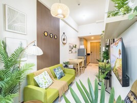 Una sala de estar moderna con un sofá verde, una mesa de comedor y una zona de cocina.