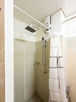 Eine Dusche mit Handbrause, Wandarmatur und Duschvorhang.
