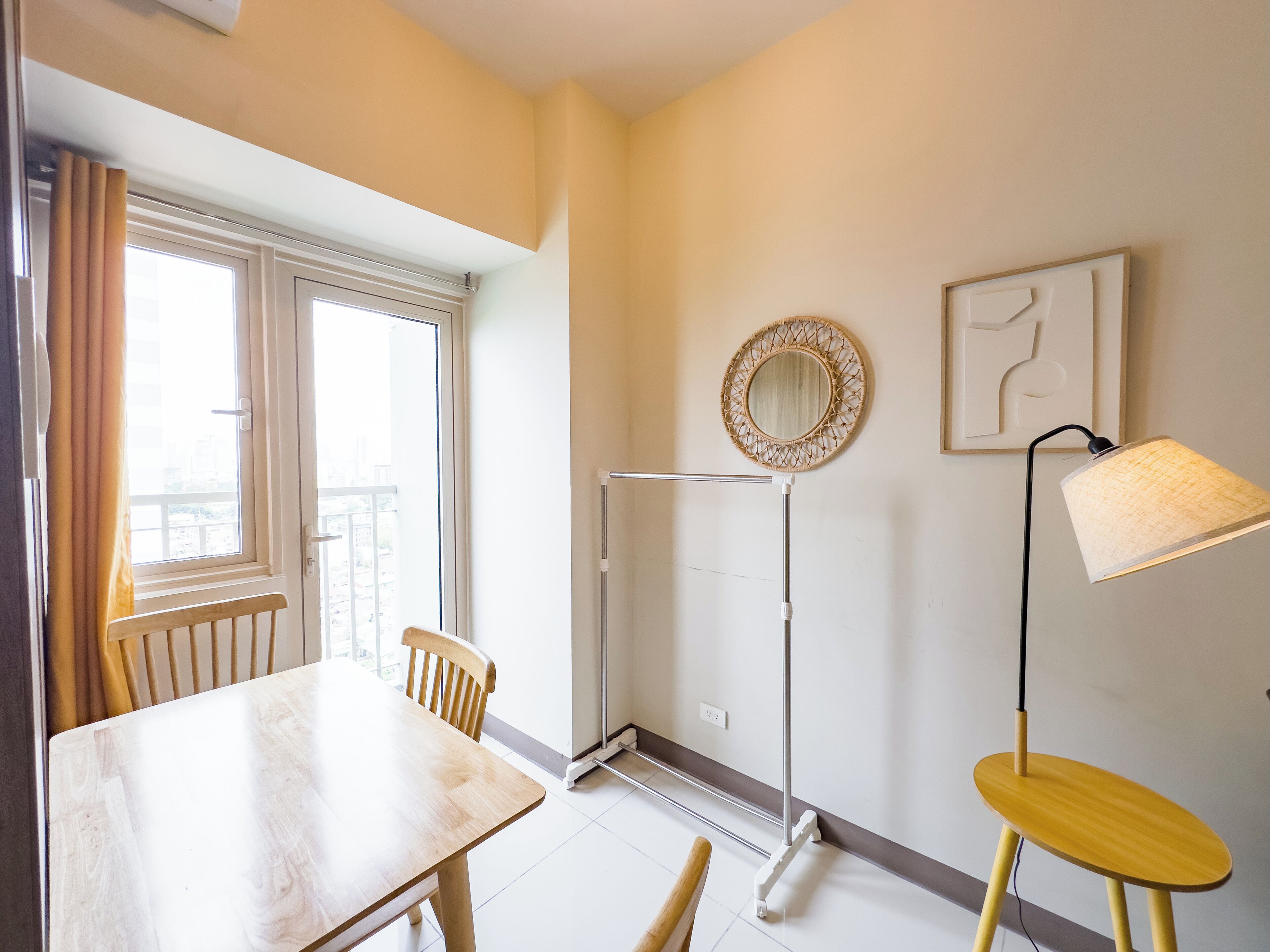 A room with a dining table, chairs, a standing heater, a floor lamp, and a wall-mounted mirror.