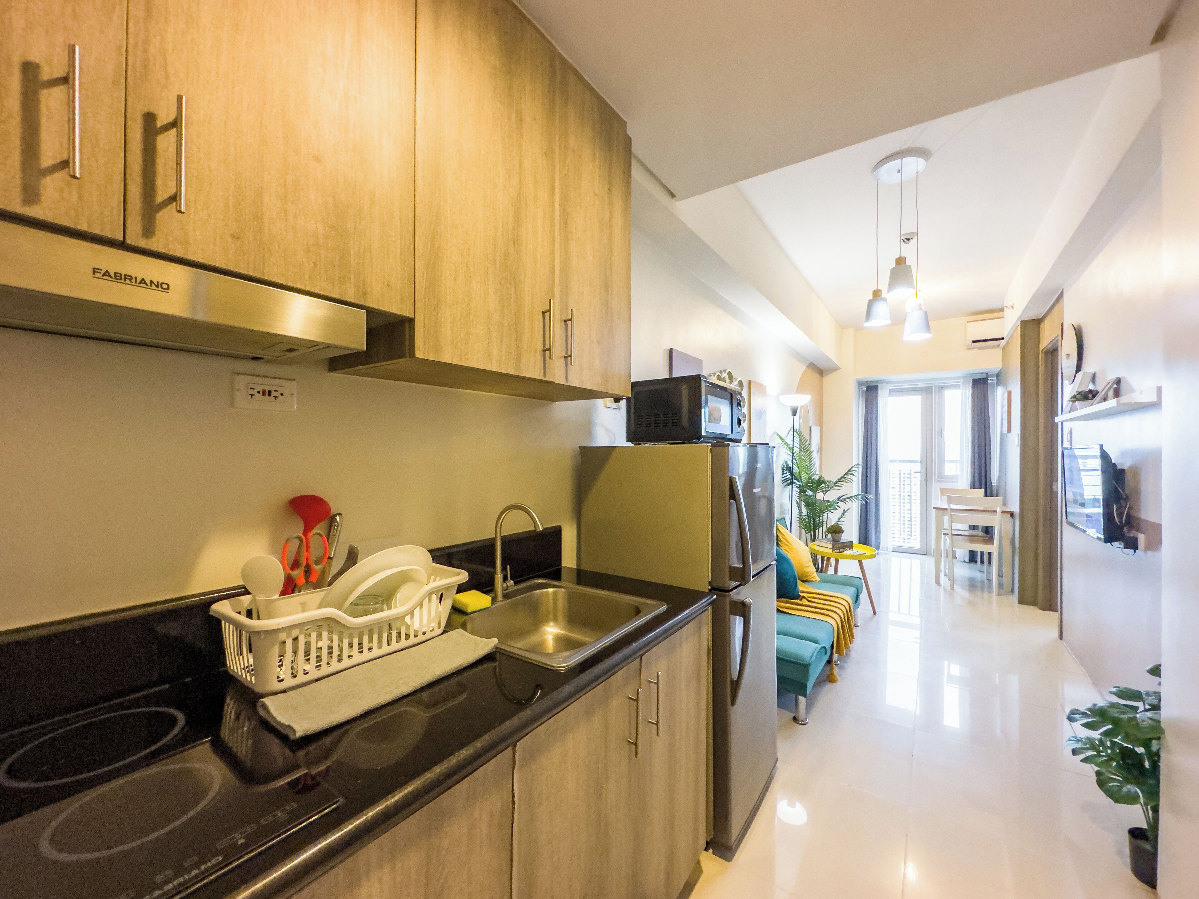 A modern kitchen with stainless steel appliances, wooden cabinets, and a black countertop.