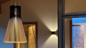 Un intérieur moderne avec un comptoir d’accueil en bois, un luminaire suspendu noir et un appliques murales.