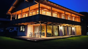 Une maison moderne à deux étages, dotée d’un patio couvert et de grandes fenêtres.