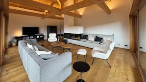 Un vaste espace de vie doté d’un haut plafond en bois, d’une cheminée et de meubles modernes.
