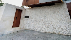 Une maison moderne à deux étages, dotée d’une façade en pierre, de grandes fenêtres et d’un toit en bois.