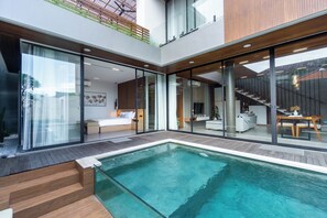 A modern house with a glass-enclosed living area, a pool, and a staircase leading to a balcony. - Villa Elena (Seminyak)