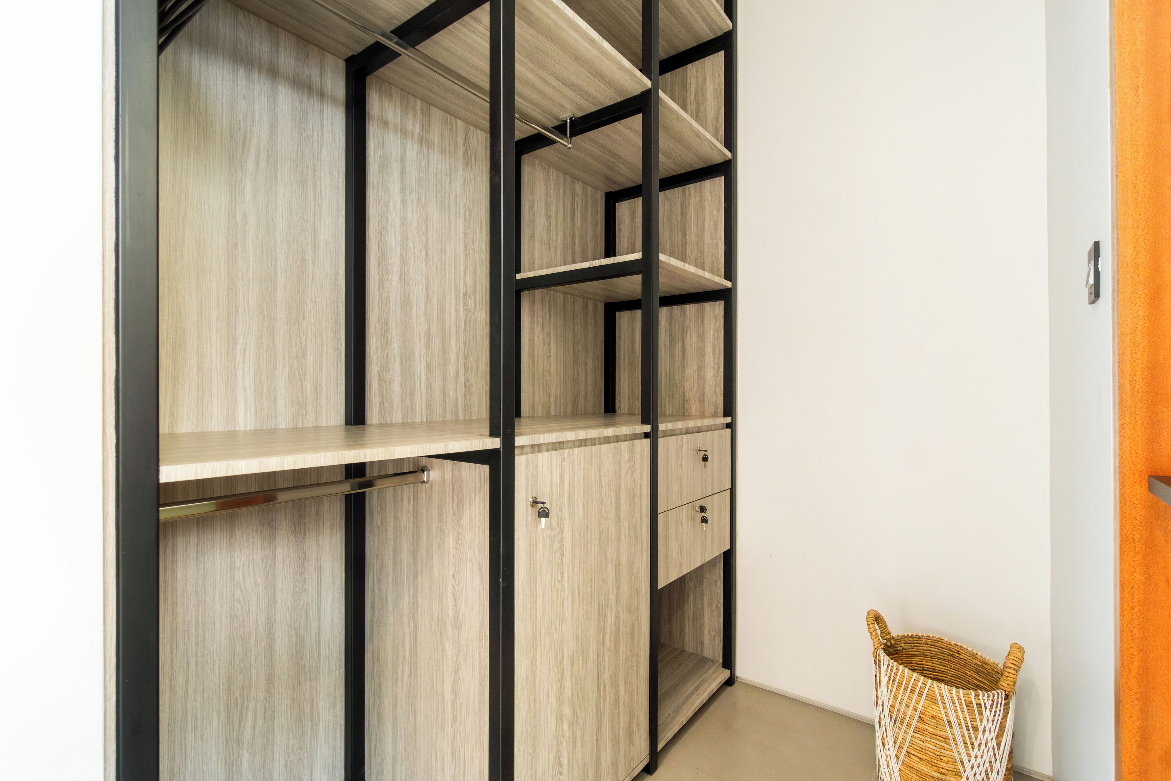 A walk-in closet with open shelves and drawers, a wicker basket, and a wooden door.