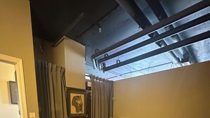 Een slaapkamer met een bed, een ventilator en een raam met gordijnen.