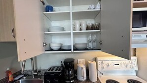 Een compacte keuken met een spoelbak, een broodrooster, een koffiezetapparaat en een fornuis.