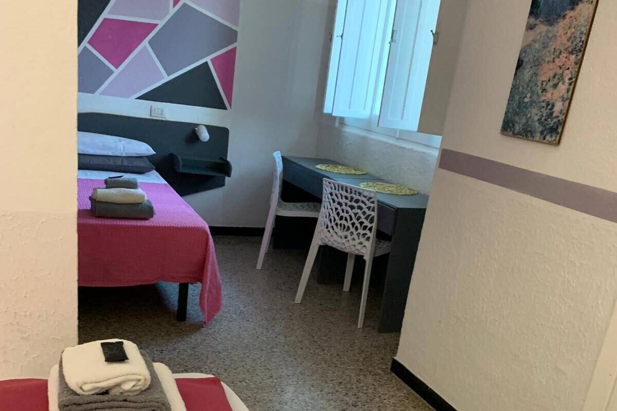 A room with a massage table, a small table with a chair, and a wall with geometric artwork.