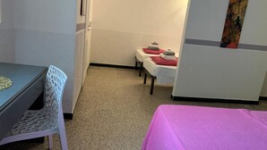 A hotel room with a dining table, a pink bed, and two small tables with towels. - Hotel Splendor (Tortoli)