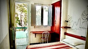 A bedroom with a bed, a desk, and a chair. There is a window with a view of trees. - Hotel Splendor (Tortoli)