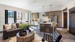 Een moderne woonkamer met een bank, salontafel en een eethoek met stoelen.